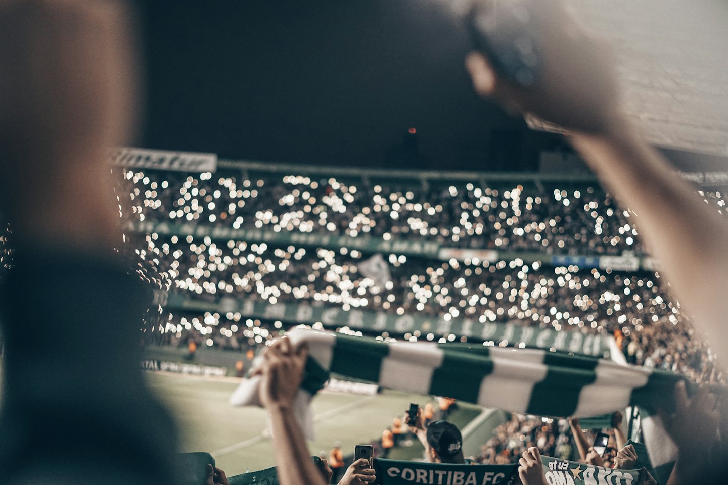 Spectator holds a green and white scarf at a stadium.