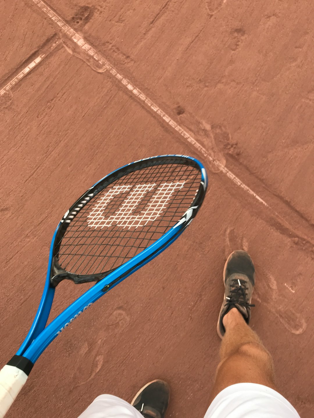 Tennis player standing on a clay court holding a racket.