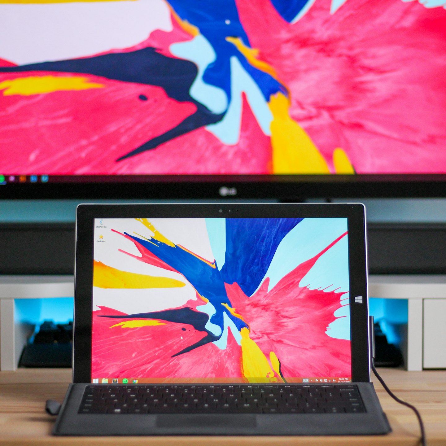 Laptop and television showing colorful abstract wallpaper.